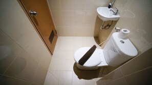 Bathroom with a toilet and sink, featuring a door and tiled walls.