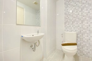 A bathroom with a white sink, a toilet, and a mirror. - Chic And Cozy Studio At Tokyo Riverside Pik 2 Apartment (Teluknaga)