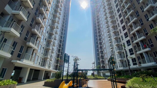 A high-rise residential building with multiple balconies and a central courtyard with exercise equipment. - Chic And Cozy Studio At Tokyo Riverside Pik 2 Apartment (Teluknaga)