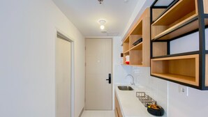 A compact kitchen with white cabinets, a wooden countertop, and a built-in sink. - Chic And Cozy Studio At Tokyo Riverside Pik 2 Apartment (Teluknaga)