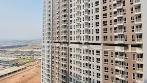 A high-rise building with multiple balconies and a view of a construction site below. - Chic And Cozy Studio At Tokyo Riverside Pik 2 Apartment (Teluknaga)