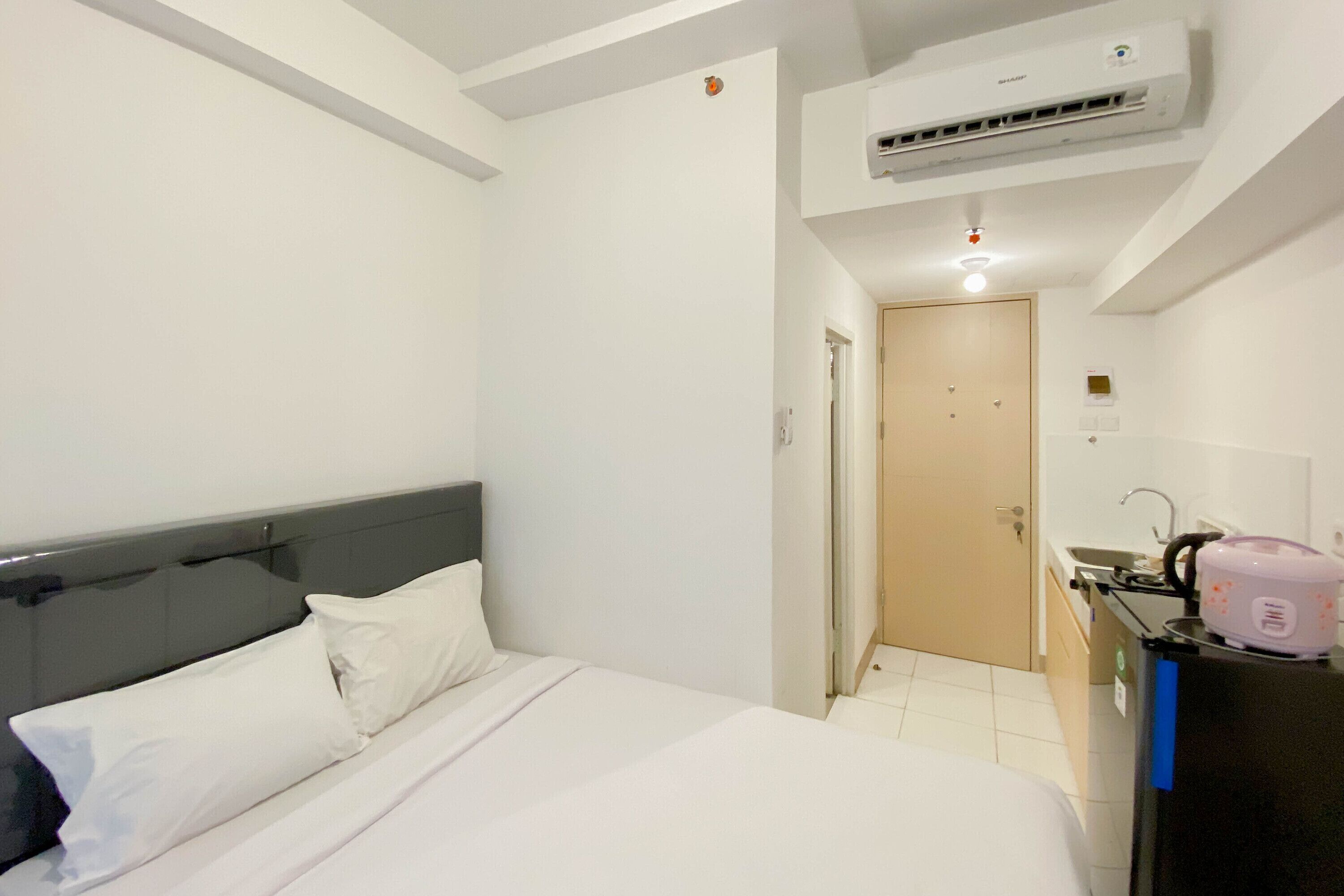 Habitación de hotel con cama, kitchenette y aire acondicionado.