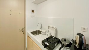 Une petite cuisine équipée d’un évier, d’une bouilloire, d’une cuisinière et d’un grille-pain.