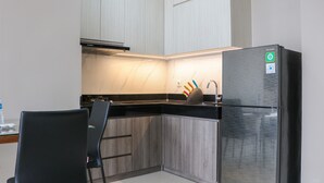 A modern kitchen with a black refrigerator, wooden cabinets, and a black countertop. - Spacious And Homey 2Br At Ciputra International Apartment (Jakarta)
