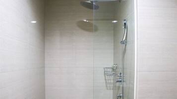 A glass-enclosed shower with a handheld showerhead, a wall-mounted faucet, and a showerhead.