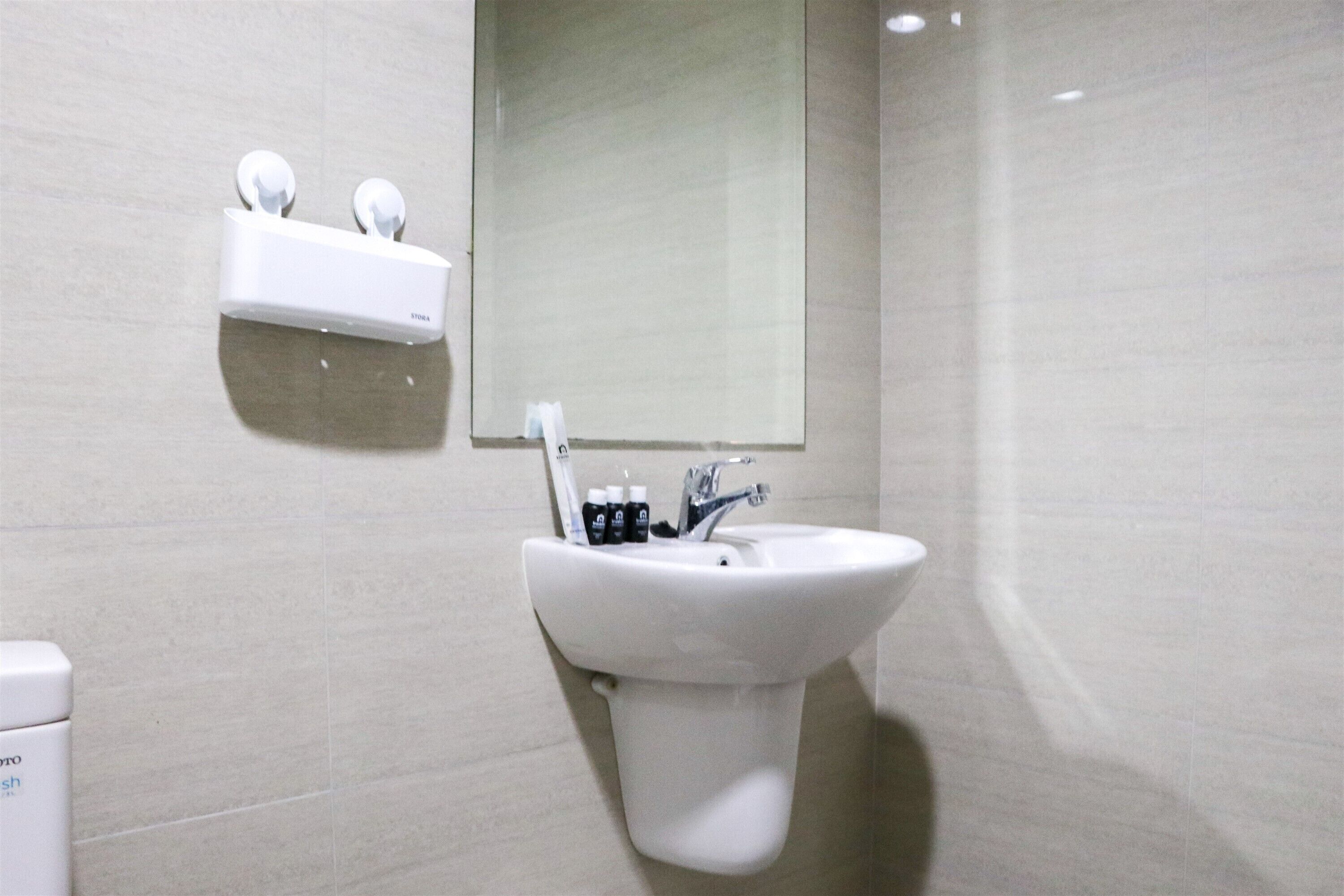 Une salle de bain avec un lavabo blanc, un miroir et un distributeur de savon.