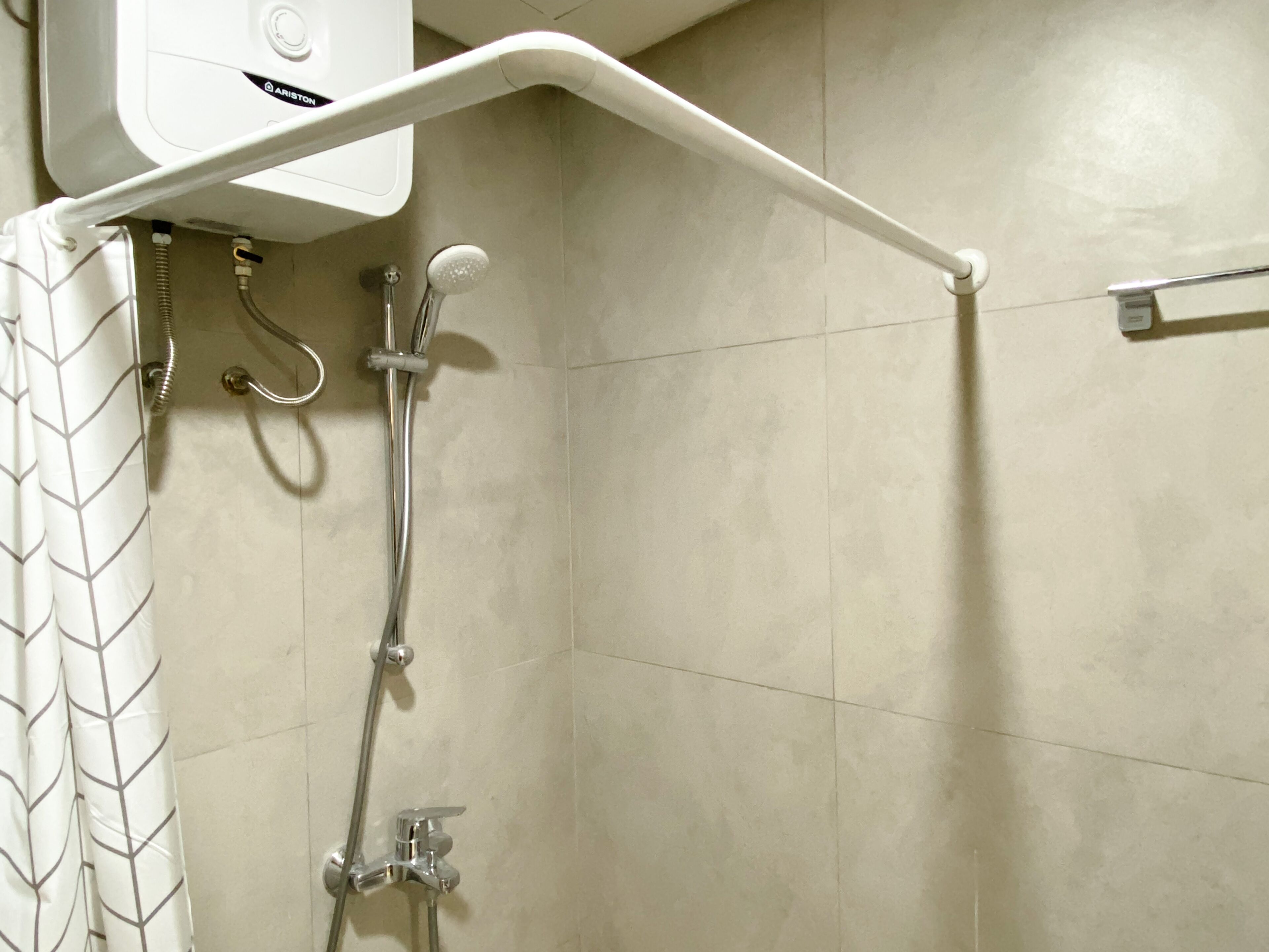 A shower with a white control panel, a handheld showerhead, and a handheld faucet.