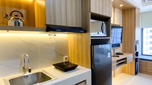 A modern kitchen with a stainless steel sink, a built-in microwave, and a refrigerator. - Homey And Warm Studio Room Pollux Chadstone Apartment (Cikarang)