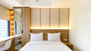 A modern hotel room with a large bed, a desk, and a chair. - Homey And Warm Studio Room Pollux Chadstone Apartment (Cikarang)