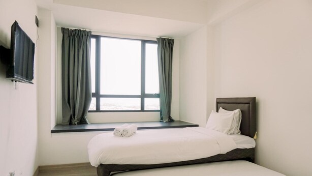 Een hotelkamer met een bed, een raam met gordijnen en een wandgemonteerde flatscreen televisie.
