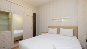 A neatly arranged hotel room with a bed, a wardrobe, and a bedside table. - Modern And Good Deal 2Br At Transpark Cibubur Apartment (Depok)