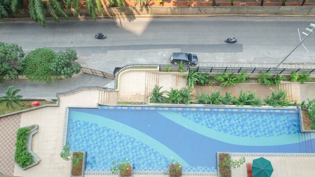 A swimming pool with a checkered pattern, surrounded by planters and a fence. - Modern And Good Deal 2Br At Transpark Cibubur Apartment (Depok)