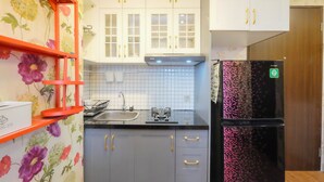 A kitchen with white cabinets, a black refrigerator, and a red shelf. - Modern And Good Deal 2Br At Transpark Cibubur Apartment (Depok)