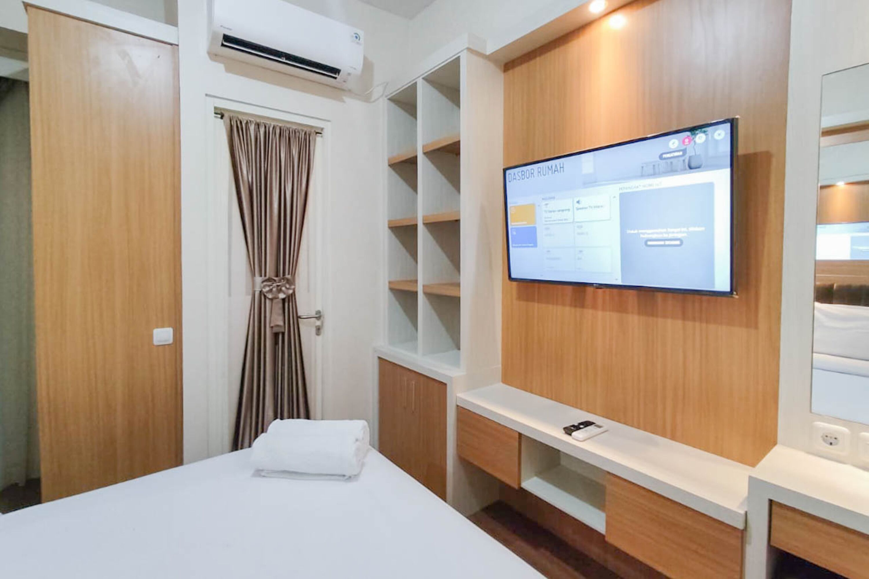 Ein Hotelzimmer mit Bett, Wandfernseher, Kleiderschrank und Regalelement.