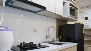 A modern kitchen with white subway tiles, a stainless steel sink, a black refrigerator, and a built-in oven. - Cozy Stay And Minimalist 1Br Tokyo Riverside Pik 2 Apartment (Teluknaga)