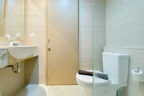 A modern bathroom with a glass shower enclosure, a white sink, and a toilet. - Well Furnished And Comfortable 2Br Apartment Gold Coast (Jakarta)