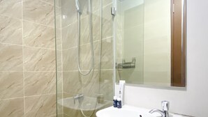 Une salle de bain avec une douche à parois de verre, un lavabo blanc et un miroir.