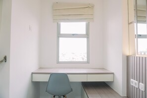 Een kleine, lichte kamer met een enkel raam, een bureau en een stoel.