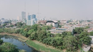 A cityscape with a mix of residential and commercial buildings, a river, and some greenery. - Homey And Cozy Stay Studio Belmont Residence Puri Apartement (Jakarta)