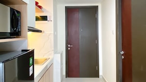 Una cocina compacta con microondas, un refrigerador pequeño y un lavamanos.