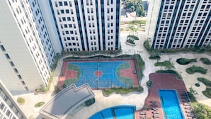 Un edificio de gran altura con cancha de baloncesto, piscina y zonas ajardinadas.