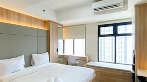 Una habitación de hotel moderna con una cama grande, un escritorio y un ventanal con vista a la ciudad.