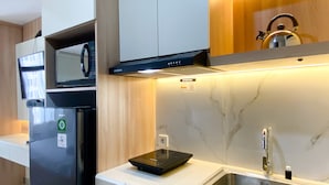 Una cocina moderna con microondas integrado, un lavamanos de acero inoxidable y una placa de cocción por inducción negra.