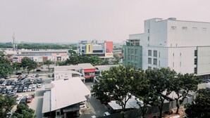 A multi-story building with a flat roof, surrounded by parked cars and trees.