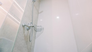 A modern shower with a handheld showerhead and a wall-mounted faucet.