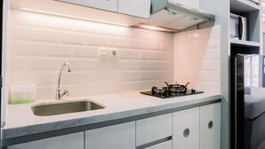 A modern kitchen with a sink, stove, and white cabinets.