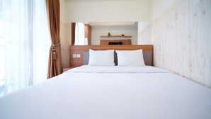 A hotel room with a wooden headboard, white bedding, and a small wooden shelf above the bed. - Strategic And Homey Studio At Tamasari Papilio Apartment (Surabaya)