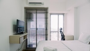 Ein Hotelzimmer mit einem Bett, einem Fernseher auf einem Schrank, einem Schreibtisch und einem Fenster mit Jalousien.