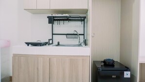 Eine kleine Küchenzeile mit Spüle, kleinem Kühlschrank und einer Arbeitsplatte mit Geschirrablage.