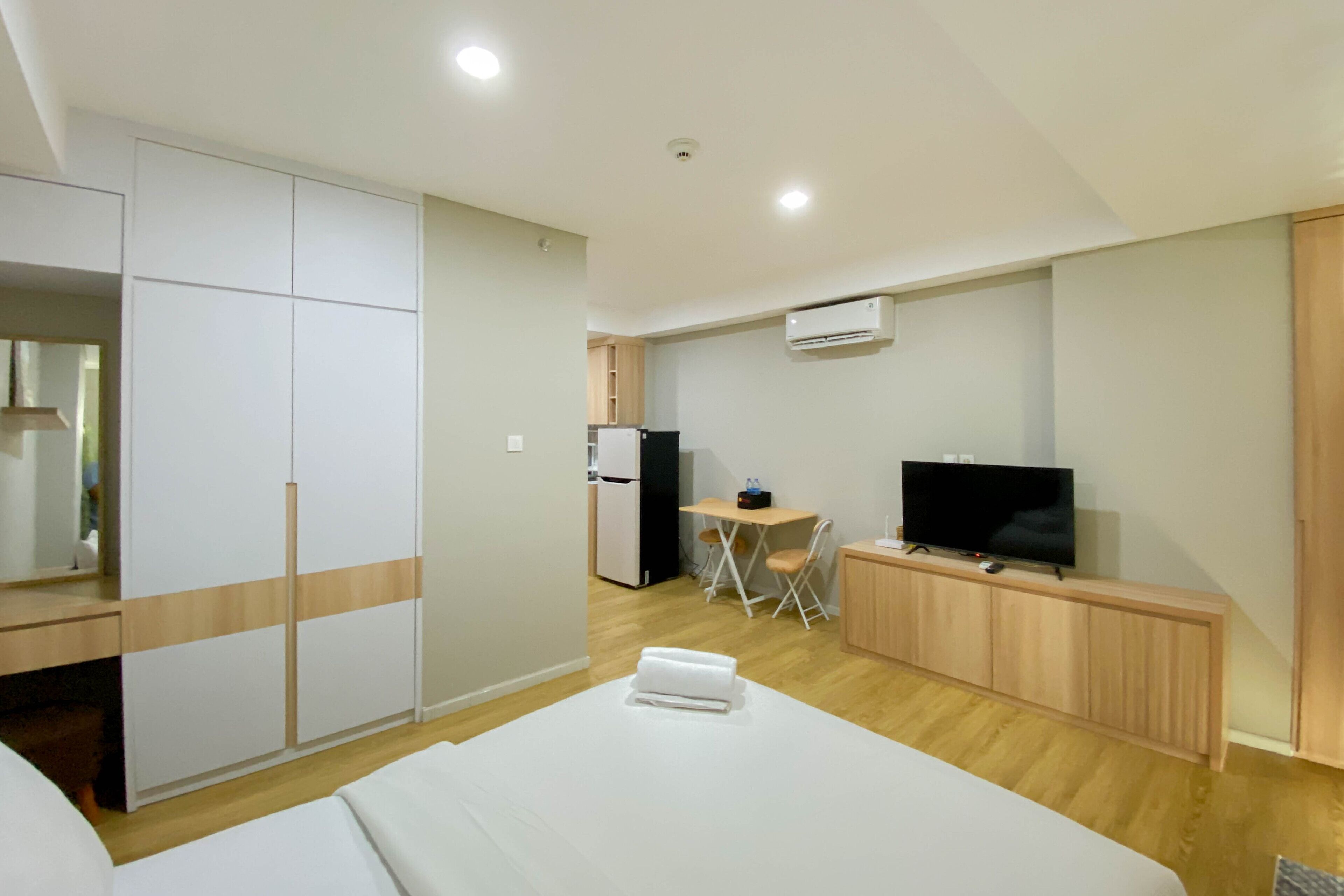 A hotel room with a bed, a desk, a television, a small table, and a wardrobe.