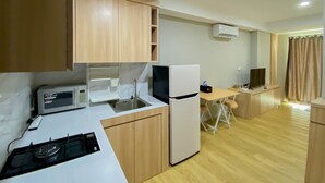 Een kleine keuken met een magnetron, gootsteen en koelkast. Er is een zithoekje met een tafel en stoelen.