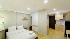 Een moderne hotelkamer met een groot bed, een klein bureau, een kitchenette en een badkamer.