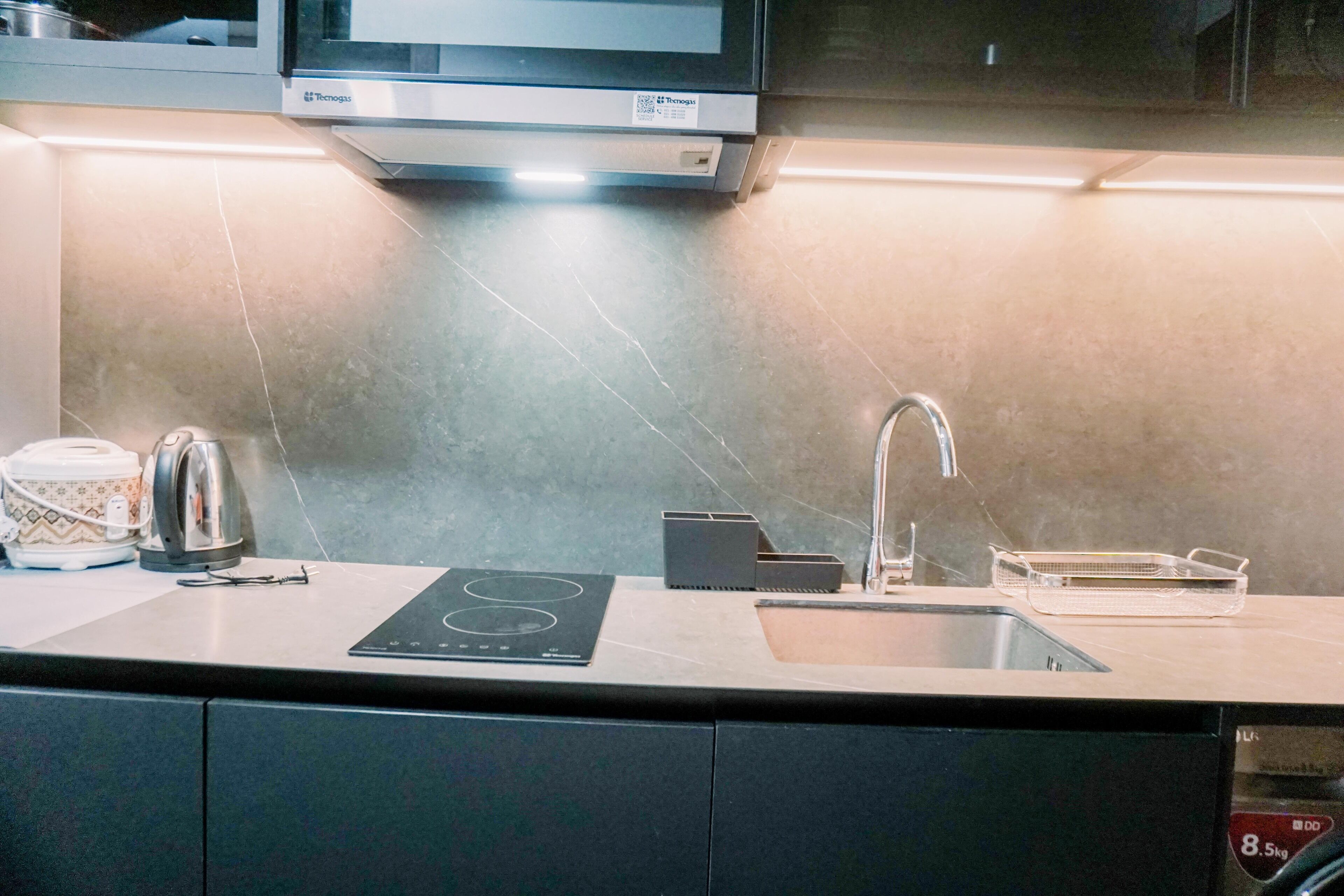 Een moderne keuken met een inbouwmagnetron, waterkoker en spoelbak.