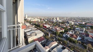 Un immeuble de grande hauteur doté d’un balcon donnant sur une zone urbaine densément peuplée, avec divers bâtiments et rues.