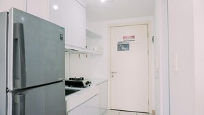 A compact kitchen with a stainless steel refrigerator, white cabinets, and a tiled floor. - Gorgeous And Strategic Studio Apartment M-Town Residence (Gading Serpong)