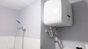 A bathroom with a white toilet, a shower with a handheld showerhead, and a wall-mounted water heater.