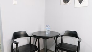 A small, round table with two black chairs, a water bottle, and two framed pictures on the wall.