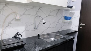 A modern kitchen with a black countertop, a sink, a built-in dishwasher, and a marble backsplash.