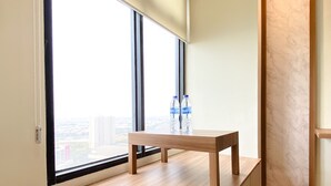 Una habitación con un ventanal grande, un banco de madera y dos botellas de agua en el alféizar.