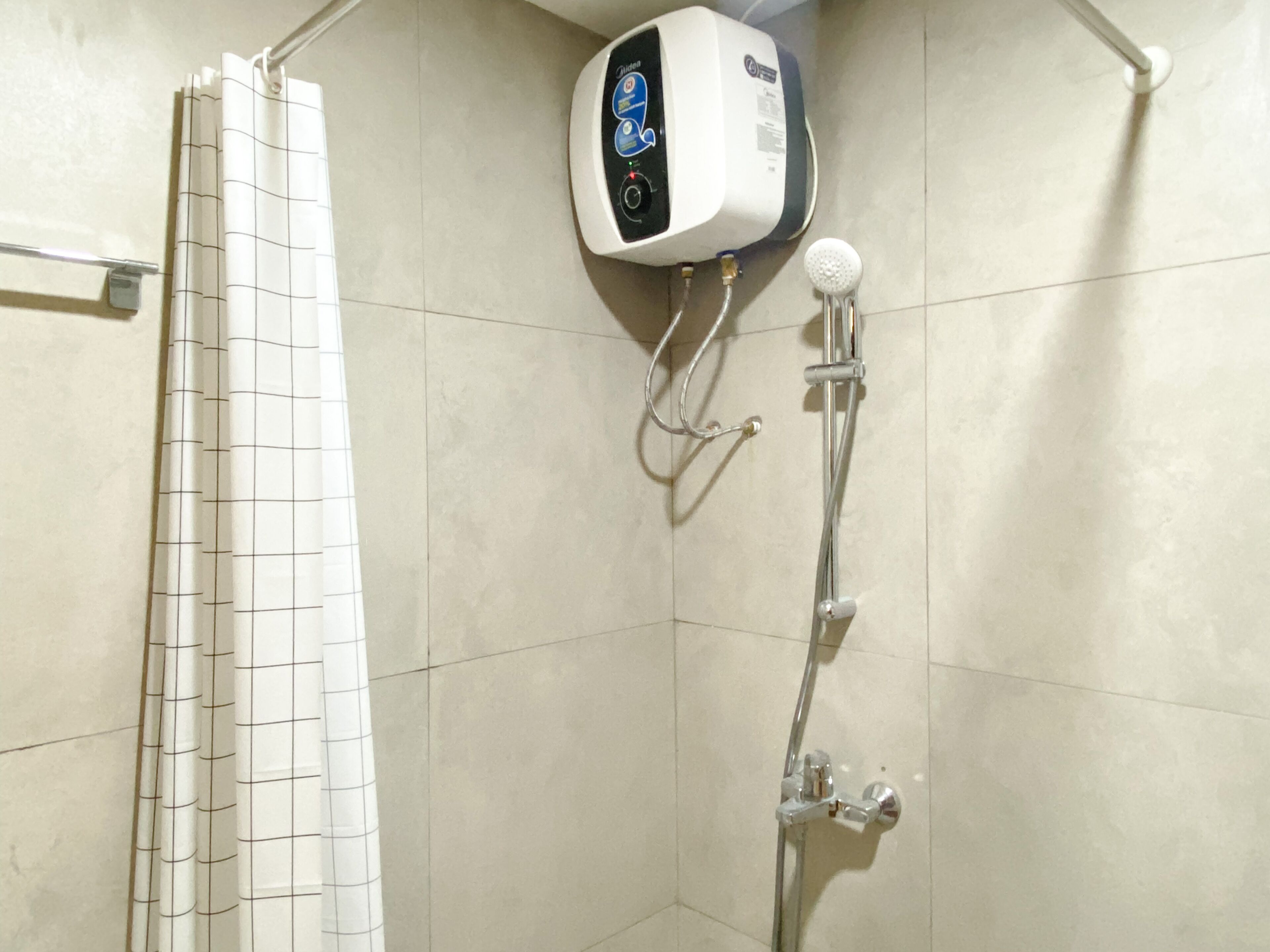 A shower area with a control panel, a handheld showerhead, and a grid-patterned shower curtain.