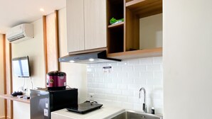 Cocina compacta con microondas integrado, refrigerador pequeño, lavamanos y estufa.