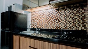 A kitchen with a black countertop, a sink, a microwave, and a tiled backsplash.