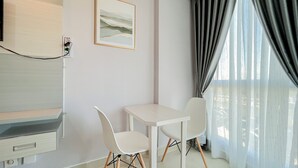 A modern room with a white table and chairs, a painting on the wall, and a window with curtains.