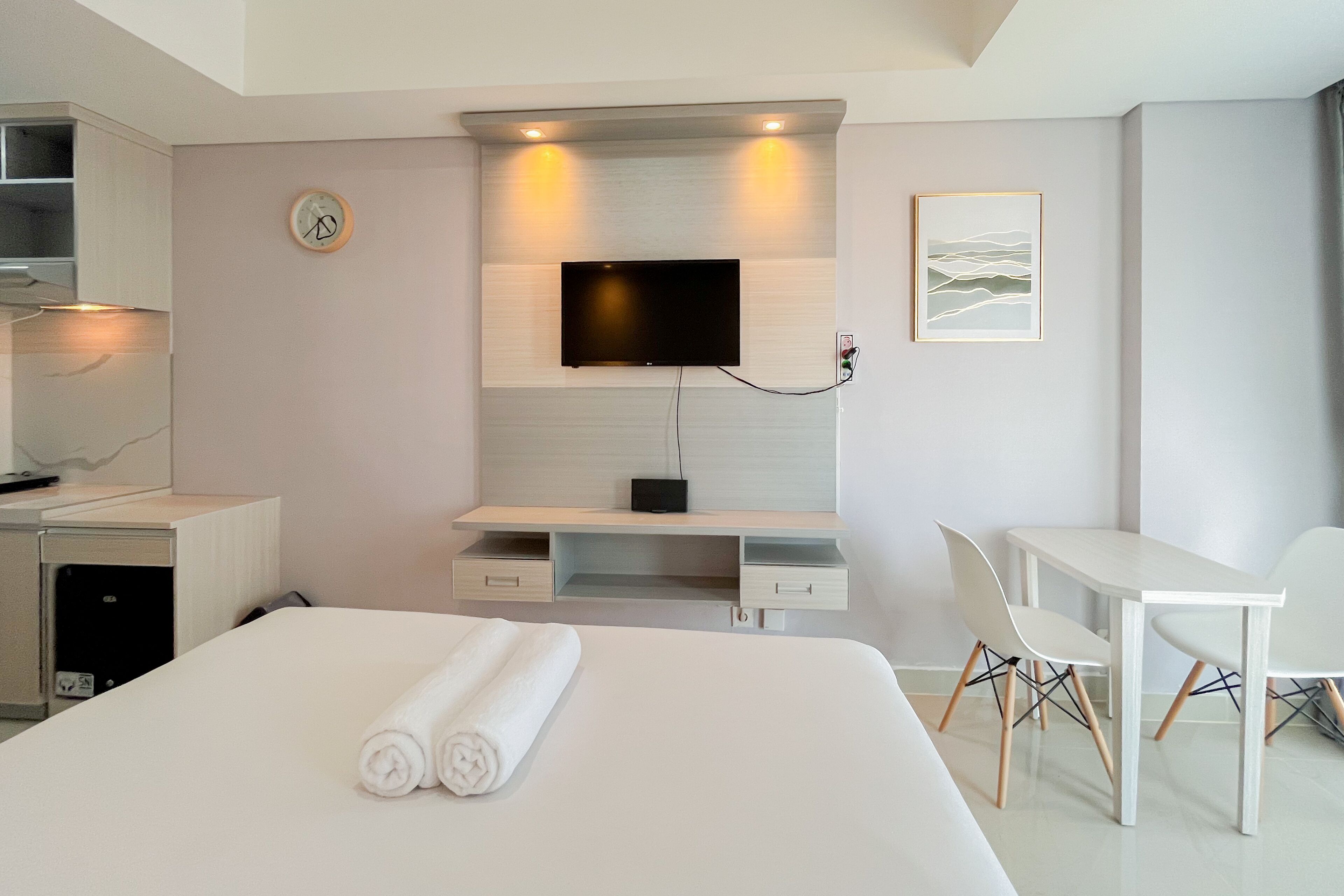 A modern hotel room with a bed, a TV mounted on the wall, a desk, and a chair.