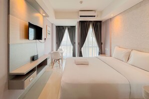 A modern hotel room with a large bed, a flat-screen TV mounted on the wall, a desk with a chair, and a window with curtains. - Best Deal And Homey Studio At Tamansari Skylounge Makassar (Makassar)