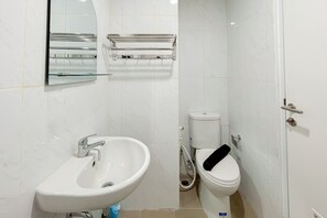 A bathroom with a white sink, a toilet, and a glass shower enclosure. - Best Deal And Homey Studio At Tamansari Skylounge Makassar (Makassar)